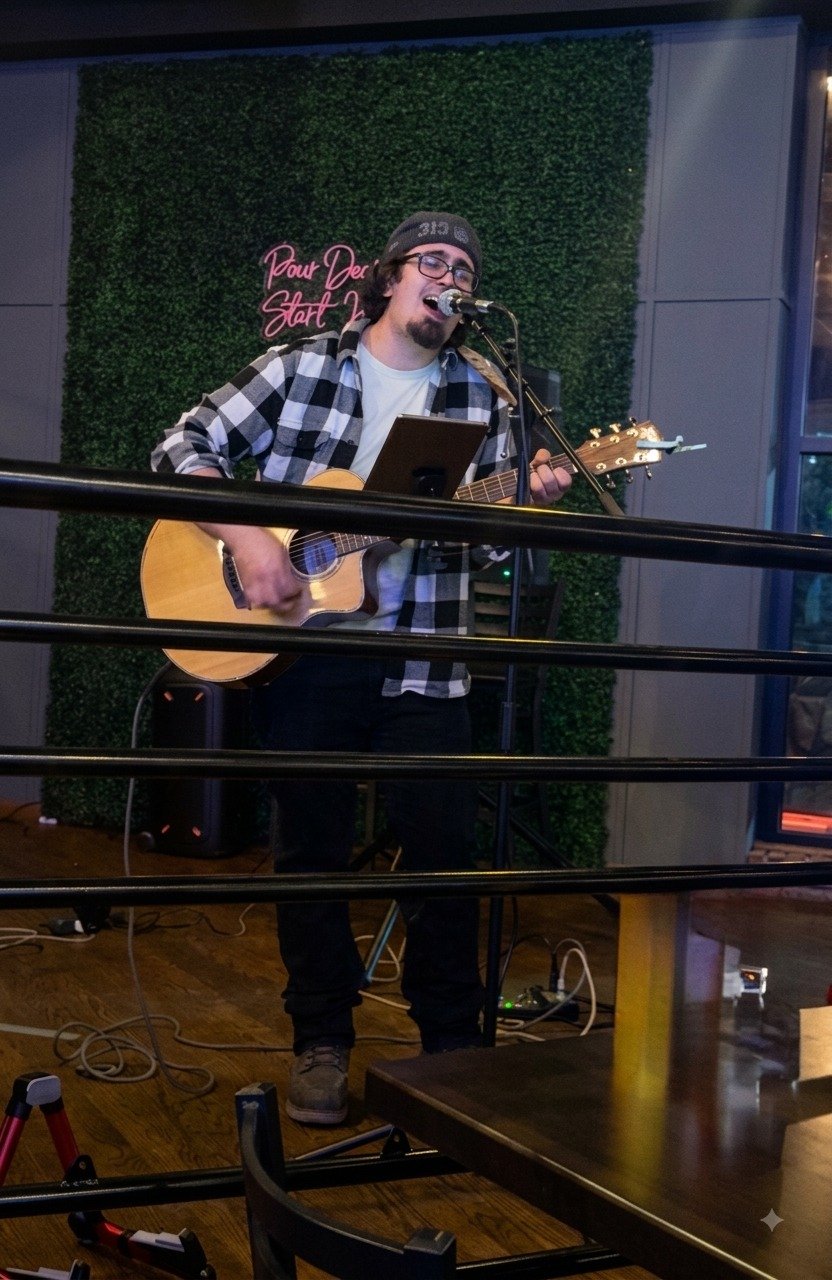 Jacob Smith performing at a taproom with a neon sign backdrop